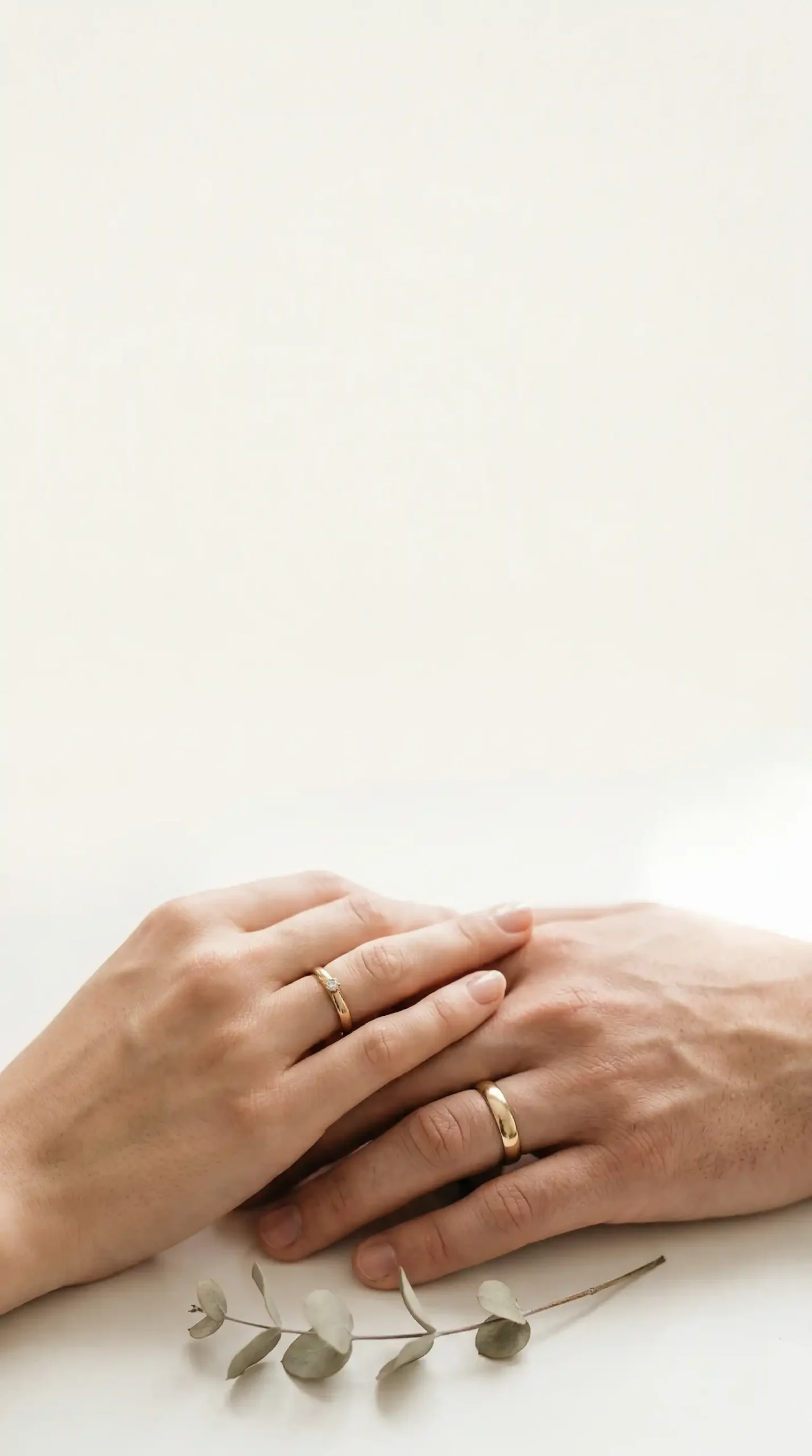 Zbliżenie na splecione dłonie nowożeńców z minimalistycznymi obrączkami ślubnymi